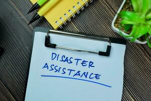 Concept of Disaster Assistance write on paperwork isolated on Wooden Table. photo