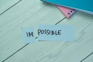 Concept of Impossible to possible write on sticky notes isolated on Wooden Table. photo