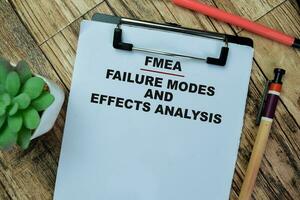 Concept of FMEA - Failure Modes and Effects Analysis write on paperwork isolated on Wooden Table. photo
