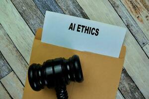 Concept of Gavel and Ai Ethics text above brown envelope isolated on on Wooden Table. photo