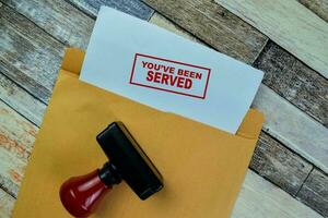 Concept of Red Handle Rubber Stamper and You've Been Served text isolated on on Wooden Table. photo