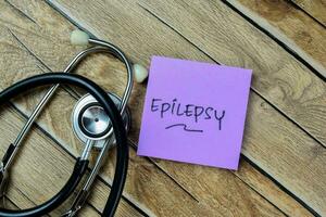 Concept of Epilepsy write on sticky notes with stethoscope isolated on Wooden Table. photo
