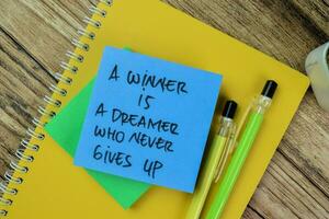 concepto de un ganador es un soñador quien Nunca da arriba escribir en pegajoso notas aislado en de madera mesa. foto