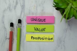 Concept of Unique, Value, Proposition write on sticky notes isolated on Wooden Table. photo