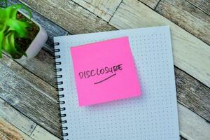 Concept of Disclosure write on sticky notes isolated on Wooden Table. photo