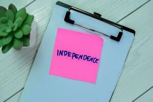 Concept of Independence write on sticky notes isolated on Wooden Table. photo