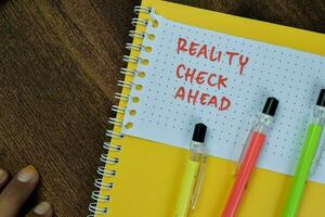 Concept of Reality Check Ahead write on sticky notes isolated on Wooden Table. photo