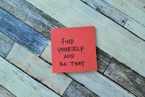 Concept of Find Yourself and Be That write on sticky notes isolated on Wooden Table. photo