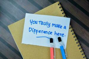 Concept of You Trully Make a Difference Here write on sticky notes isolated on Wooden Table. photo