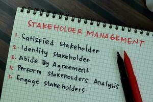 Concept of Stakeholder Management write on book with keywords isolated on Wooden Table. photo