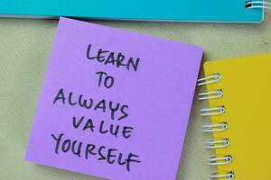 Concept of Learn To Always Value Yourself write on sticky notes isolated on Wooden Table. photo