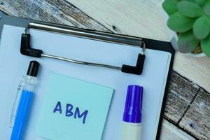 Concept of ABM write on sticky notes isolated on Wooden Table. photo