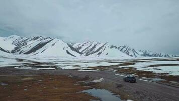 The Road Among Snowy Mountains And A Passing Car, Aerial View video