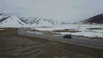 de weg tussen besneeuwd bergen en een voorbijgaan auto, antenne visie video