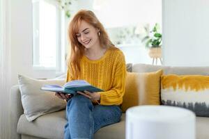 Household humidifier at home on table near woman reading on sofa photo