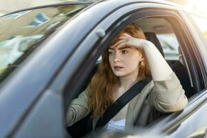 Nervous female driver sits at wheel, has worried expression as afraids to drive car by herself for first time. Frightened woman has car accident on road. People, driving, problems with transport photo