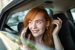 mujer de negocios multitarea mientras conduciendo, hablando en el teléfono. sonriente mujer hablando en su teléfono mientras conduciendo. mujer hablando en móvil mientras conducción foto