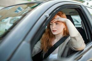 Nervous female driver sits at wheel, has worried expression as afraids to drive car by herself for first time. Frightened woman has car accident on road. People, driving, problems with transport photo