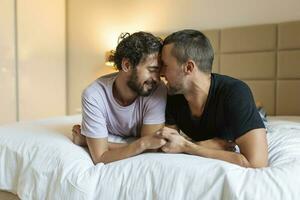 contento gay Pareja acostado abajo en el cama a hogar, abrazando y galanteo. lgbt gay Pareja amor momentos felicidad concepto foto