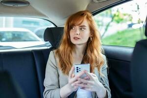 Beautiful Businesswoman is Commuting from Office in a Backseat of Her Luxury Car. Entrepreneur Passenger Traveling in a Transfer Taxi in Urban City Street photo