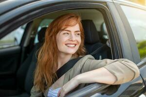 hermosa joven mujer conducción su nuevo coche a puesta de sol. mujer en coche. cerca arriba retrato de agradable mirando hembra con alegre positivo expresión, mujer en casual vestir conducción un coche foto