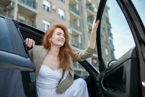 Beautiful young woman opens the car door. Attractive woman getting out of the car. photo