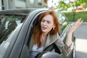 displeased woman looking out from side window and pointing with hand while driving car on blurred foreground photo