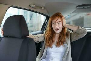scared woman holding hand on head while riding in car on blurred foreground photo