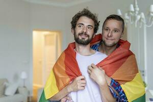 cariñoso masculino gay Pareja adentro. hombre abrazando su novio desde detrás a hogar. gay Pareja celebrando orgullo mes foto