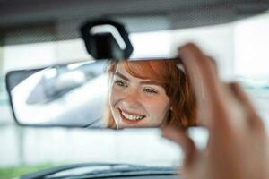 mujer mano ajustando posterior ver espejo de su coche. contento joven mujer conductor mirando ajustando posterior ver coche espejo, haciendo Por supuesto línea es gratis visibilidad es bueno foto