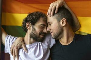 apasionado gay Pareja haciendo fuera con lgbtq bandera en el antecedentes. joven gay Pareja unión afectuosamente adentro. foto