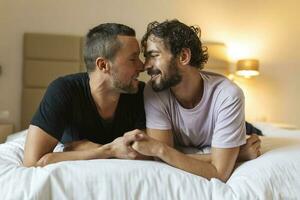 contento gay Pareja acostado abajo en el cama a hogar, abrazando y galanteo. lgbt gay Pareja amor momentos felicidad concepto foto