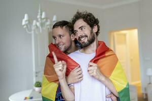 cariñoso masculino gay Pareja adentro. hombre abrazando su novio desde detrás a hogar. gay Pareja celebrando orgullo mes foto