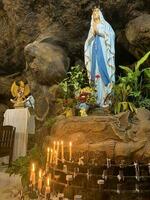 estatua de santo Virgen María en romano católico iglesia, en el cueva de Virgen María, en un rock cueva capilla católico Iglesia con tropical flores alrededor foto