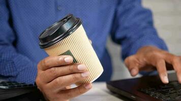 hand- Holding papier koffie kop en werken Aan laptop video