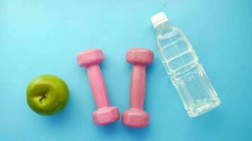 Fresh drinking water, apple and a pink color dumbbell on table video
