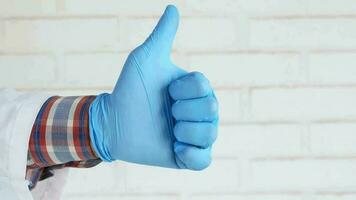 hand in medical gloves showing a thumb-up video
