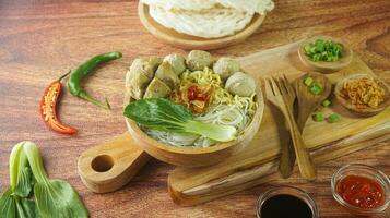 Meatball, in Indonesia known as Bakso or Baso. Served with noodles vegetables chili sauce in a bowl on white background. Close up top view flat lay photo