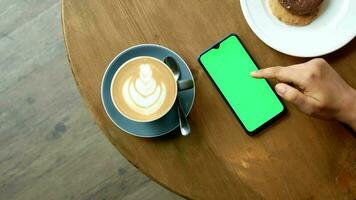 joven mujer mano utilizando inteligente teléfono con tarde café y galletas en mesa video