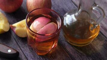 Vinagre de manzana en botella de vidrio con manzana verde fresca en la mesa video