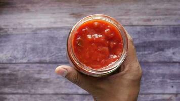 tomate salsa en un pequeño tarro con Fresco tomate en mesa , video