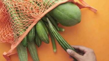 tomando vegetal fuera desde reutilizable bolso en naranja antecedentes video