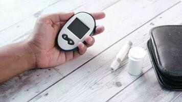 man's hand holding glucose meter on table video