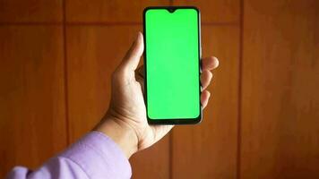 Cerca de la mano del hombre joven con un teléfono inteligente con pantalla verde video