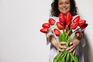 Details on bouquet of red tulips in hands o beautiful smiling woman, dressed in Ukrainian traditional embroidered dress photo