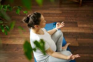 Spiritual and emotional concept of harmony in pregnancy and maternity time. Pregnant woman practicing yoga. Top view photo