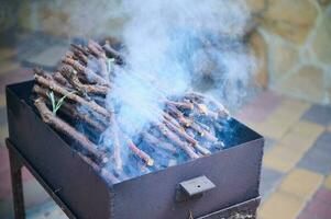 Smoke coming from a hot barbecue fire over a black grill photo