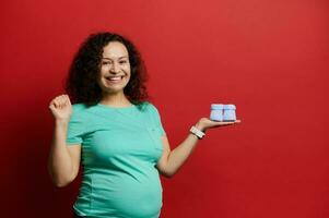 embarazada mujer con de punto azul bebé botines para su recién nacido bebé expresando positivo emociones desde maternidad el embarazo foto