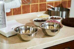 Metal bowls on a kitchen countertop with electric food processor and ingredients photo