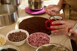 Close-up woman's hands holding a cup with strong coffee and soaking baked chocolate biscuit, preparing festive cake photo